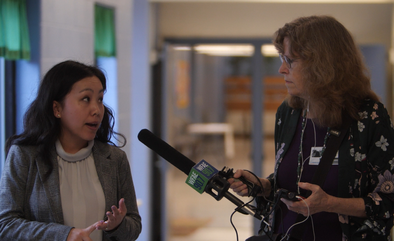 A female journalist holds a microphone to interview a woman.